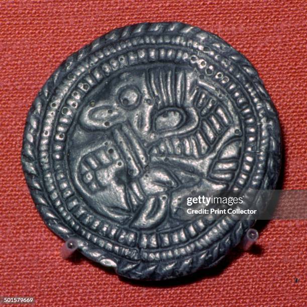 Viking cast pewter disc-brooch from York. It is decorated in the Jellinge style with a backwards-facing quadruped whose tongue extends and interlaces...