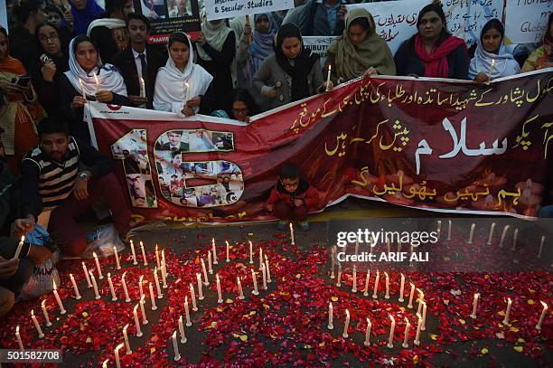 Pakistani civil society activists gather around lighted candles in Lahore on December 16 on the first anniversary of an attack on Army Public School...