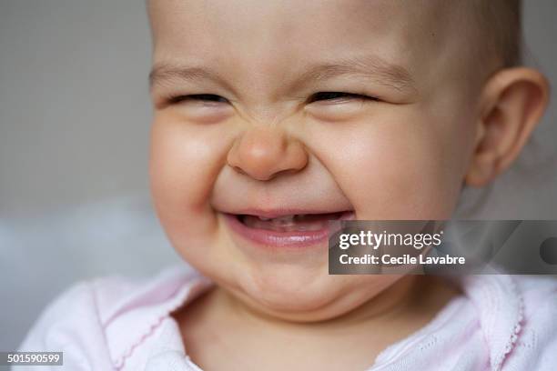 close-up portrait of baby giggling - augen zukneifen stock-fotos und bilder