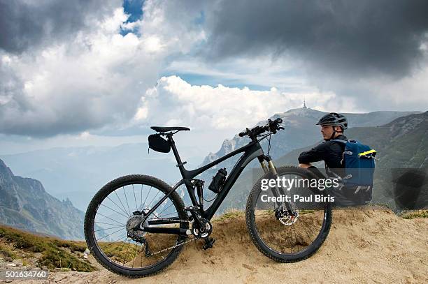 young man standing on rock formation with mountain bike, omu peak 2507m - sinaia stock pictures, royalty-free photos & images