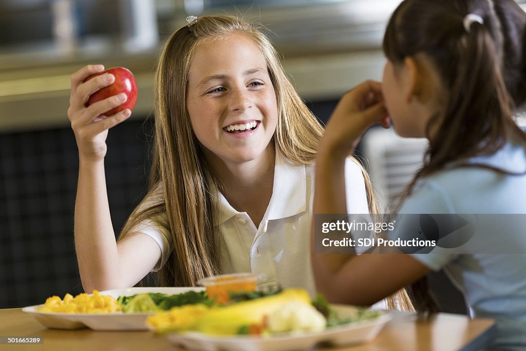 Preteen Chica comer saludable el almuerzo con amigos en la escuela cafeteria