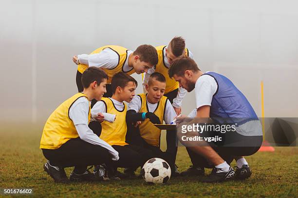 coach giving instruction to his kids soccer team. - coach stock pictures, royalty-free photos & images