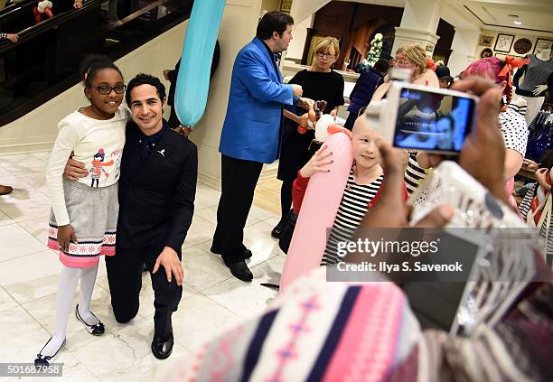 Zac Posen poses with St. Jude's patient child Marcelle at Brooks Brothers holiday celebration with St. Jude Children's Research Hospital Brooks...