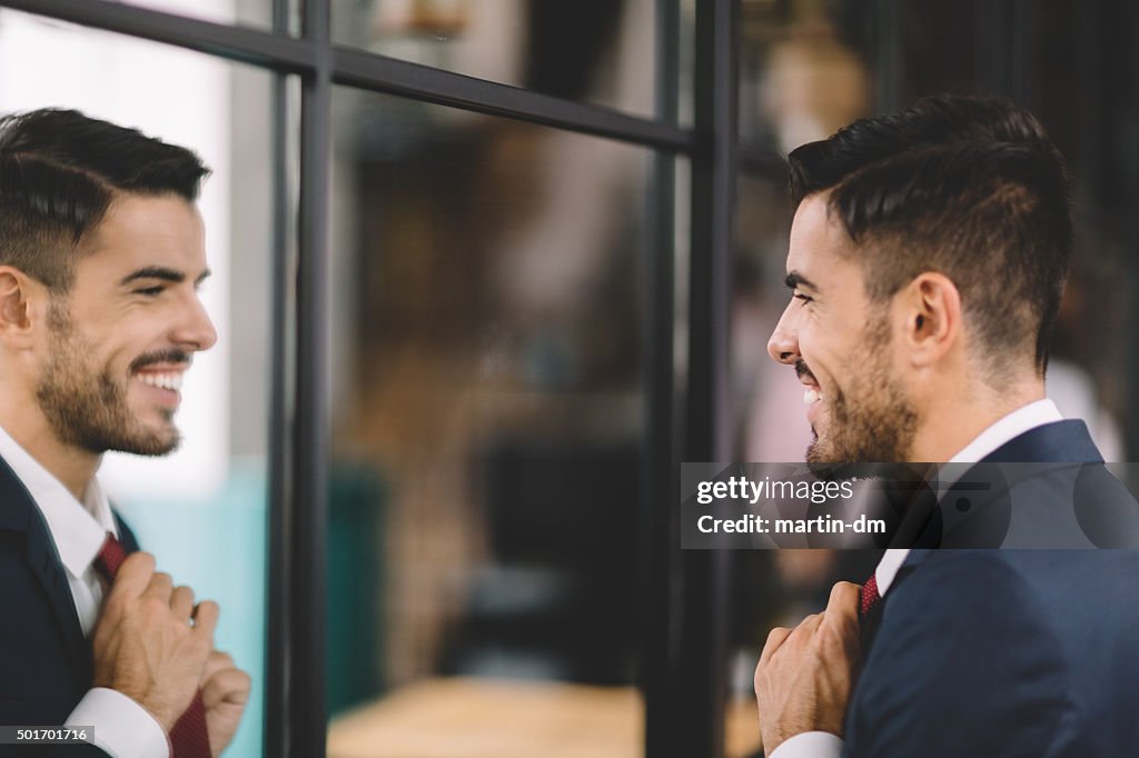 Businessman getting dressed in front of the mirror