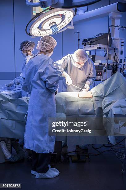 surgeons performing operation on patient in operating theatre - performing arts event stockfoto's en -beelden