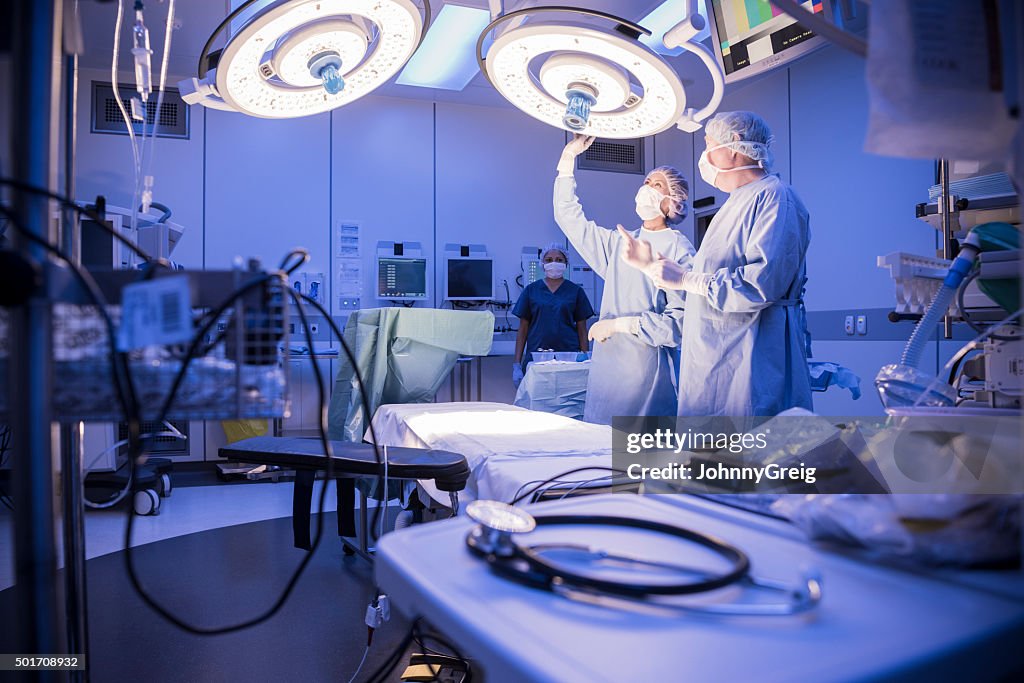 Surgeons adjusting lights in hospital operating theatre