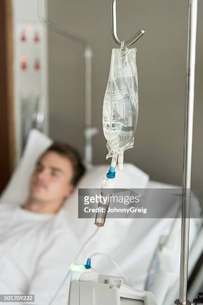 iv line and bag with male patient in hospital bed - hospital bed with iv stock pictures, royalty-free photos & images