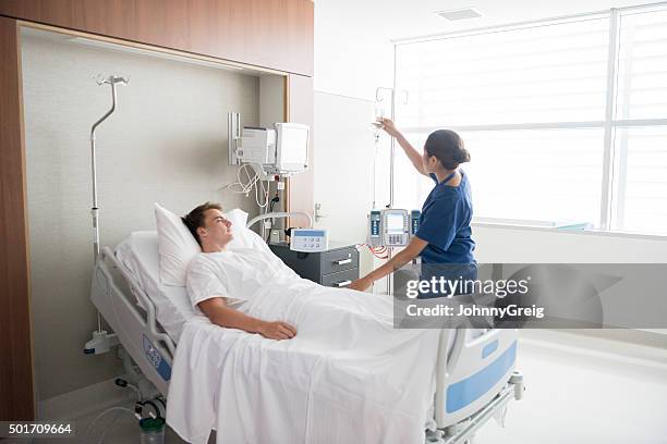 female nurse tending to male patient in hospital bed - young adult patient stock pictures, royalty-free photos & images