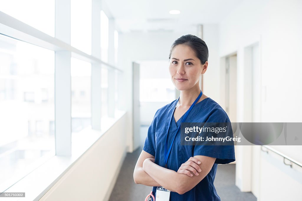 Chinese female doctor in hospital corridor with arms folded, portrait