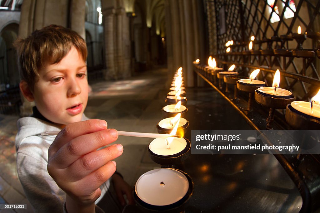 Boy lighting candles in cathedral