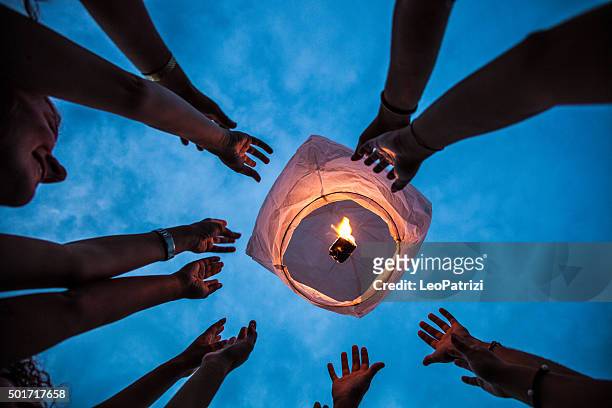 lighting a paper lantern in the air - chinese lantern night stock pictures, royalty-free photos & images