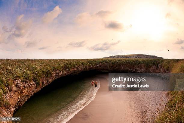 Couple walks in ocean in hidden beach w/rocky cove