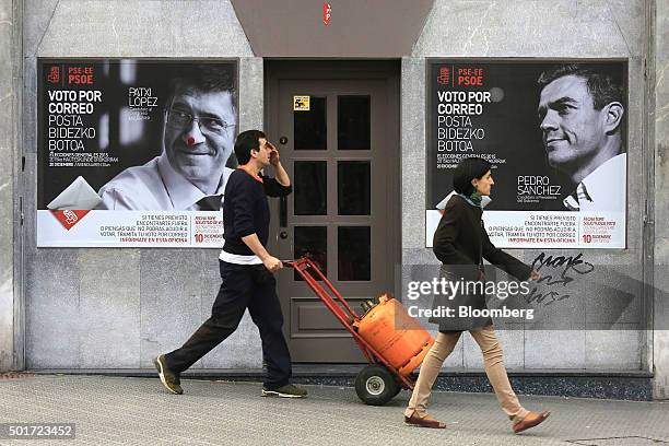 Pedestrians pass election posters for the Spanish Socialist Workers' Party with Patxi Lopez, leader of the party for Biscay, left, and Pedro Sanchez,...