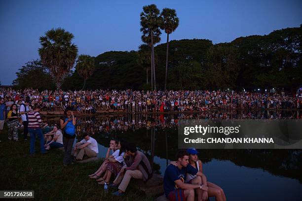 In this photograph taken on December 12 hundreds of tourists wait by the pond to see and photograph the sunrise behind the Angkor Wat Temple in Siem...