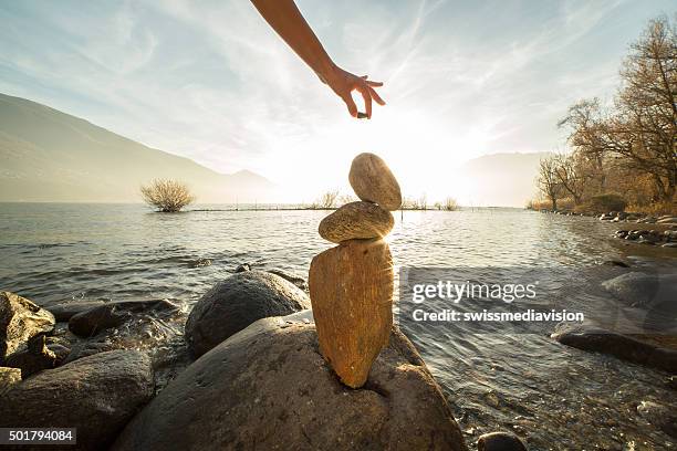 detalles de la persona para apilamiento rocks junto al lago - equilibrio fotografías e imágenes de stock