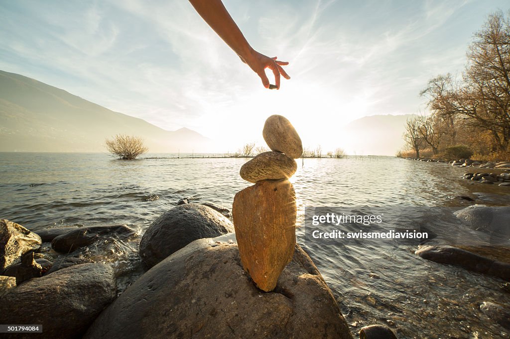 Detail of person stacking rocks by the lake