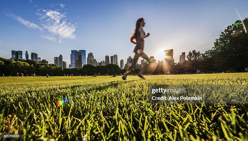 Girl runs in front of Manhattan skyline in Central Park