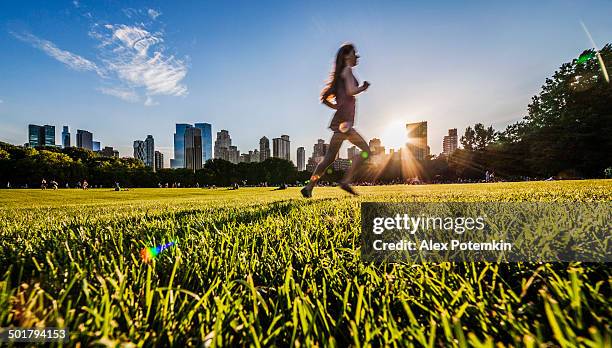 girl runs in front of manhattan skyline in central park - alex potemkin or krakozawr latino fitness stock pictures, royalty-free photos & images
