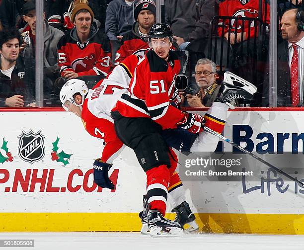 Dmitry Kulikov of the Florida Panthers is checked into the boards by Sergey Kalinin of the New Jersey Devils during the first period at the...