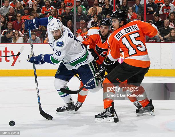 Michael Del Zotto and Brandon Manning of the Philadelphia Flyers battle for the loose puck with Chris Higgins of the Vancouver Canucks on December...