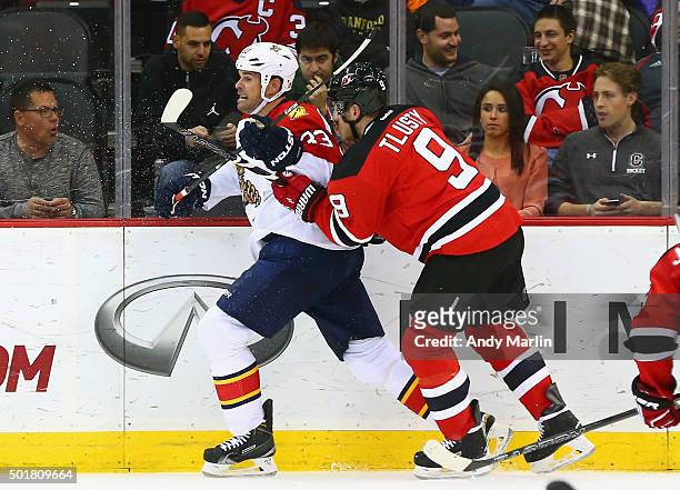 Willie Mitchell of the Florida Panthers is checked near the boards by Jiri Tlusty of the New Jersey Devils during the game at the Prudential Center...