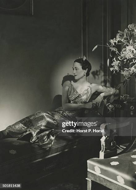 The Duchess of Windsor wearing a lame gown, reclining on a chaise.