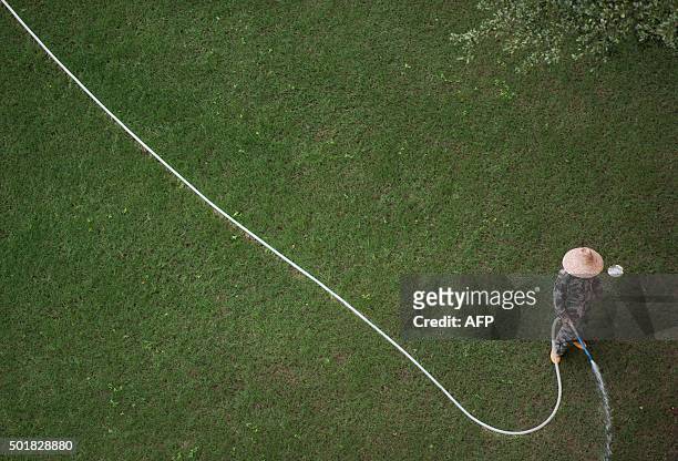 This picture taken on December 17, 2015 shows a gardener watering the grass in a hotel complex in Sanya, in southern China's Hainan province. AFP...