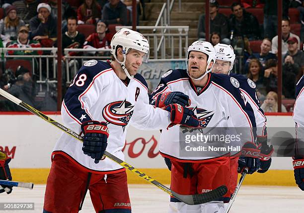 Boone Jenner of the Columbus Blue Jackets congratulates teammate David Clarkson after Clarkson's third period goal against the Arizona Coyotes at...