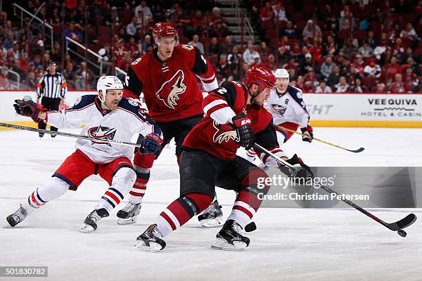 Nicklas Grossmann of the Arizona Coyotes skates with the puck ahead of David Clarkson of the Columbus Blue Jackets and Michael Stone during the third...