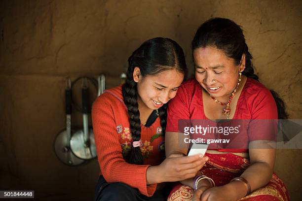 indoor image of asian daughter and mother sharing mobile phone. - nepal stock pictures, royalty-free photos & images