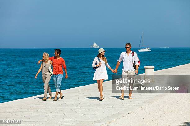 young people walking across boardwalk, boats in background, zadar, croatia - zadar croatia stock pictures, royalty-free photos & images