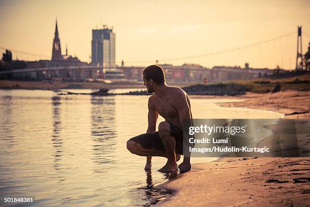 young man on the beach, city in background, drava river, osijek, croatia - semi dress stock pictures, royalty-free photos & images