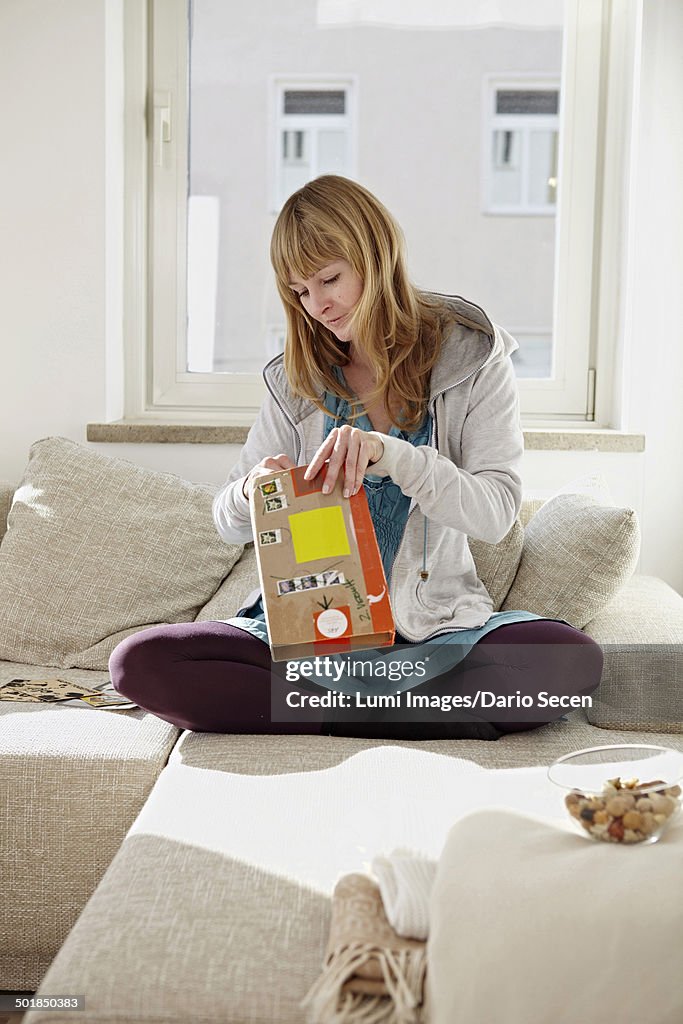 Woman Unpacking Parcel On Sofa