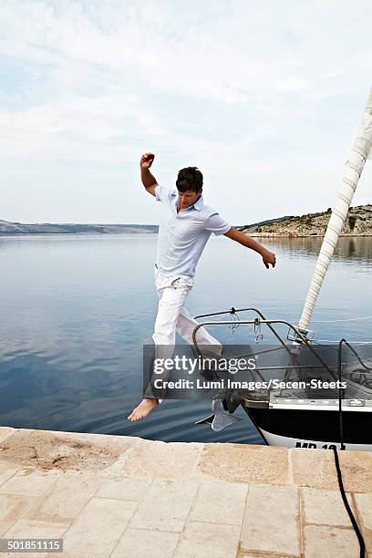 croatia, young man jumping onto pier - barefoot landing stock pictures, royalty-free photos & images