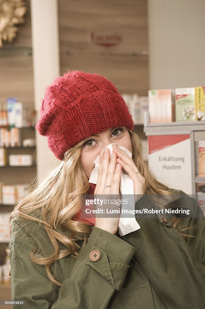 Woman In Pharmacy Blowing Nose, Munich, Bavaria, Germany