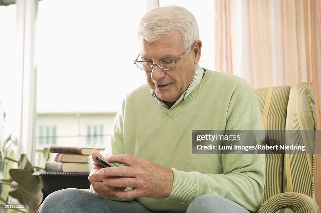 Senior man using phone in nursing home, Bavaria, Germany