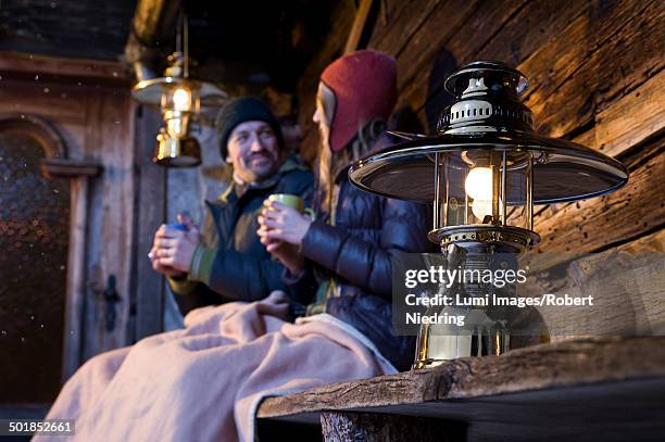 couple sitting on wooden bench in front of log cabin, tyrol, austria, europe - chalet mountain foto e immagini stock