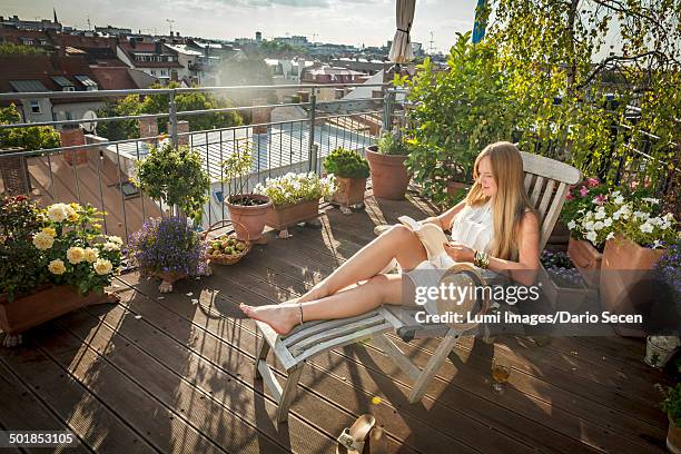 woman sunbathing on balcony, munich, bavaria, germany, europe - deck chair 個照片及圖片檔