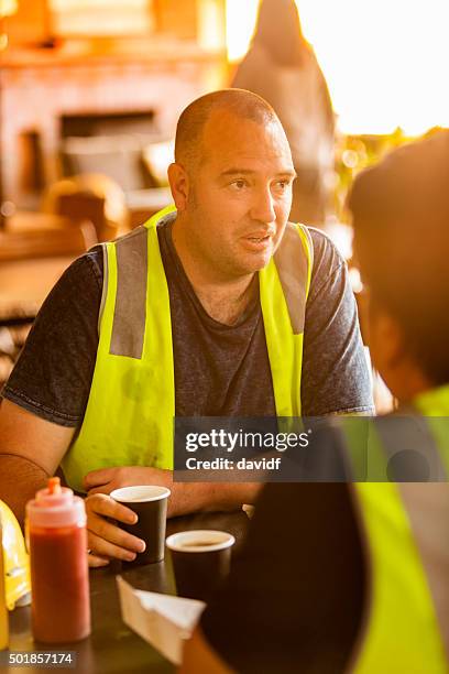 workmen on a coffee break in high visibility clothes - food and drink industry stockfoto's en -beelden