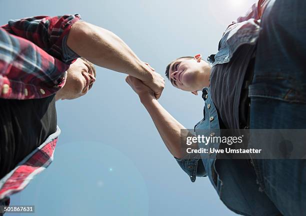 view from below of young men, shaking hands - masculinidade imagens e fotografias de stock