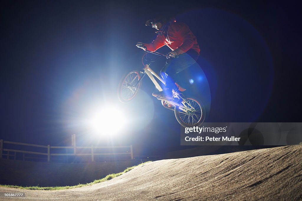 BMX-cyclist jumps his bike at night time