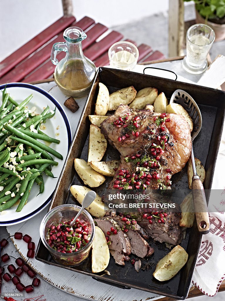 Still life of roast lamb with pomegranate seeds and vegetables