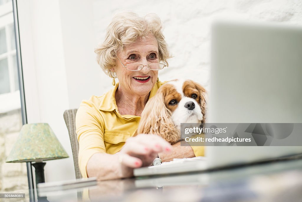 Senior woman with dog, using laptop