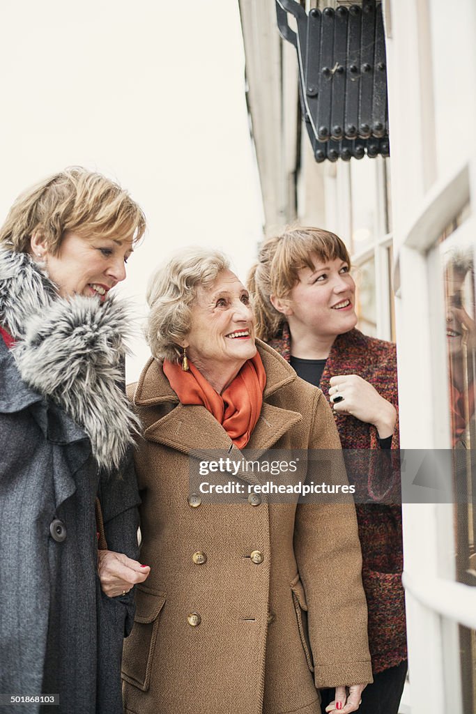 Senior woman with daughter and granddaughter, looking in window