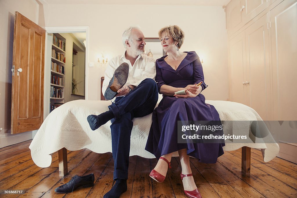 Couple sitting on bed, man putting on shoes