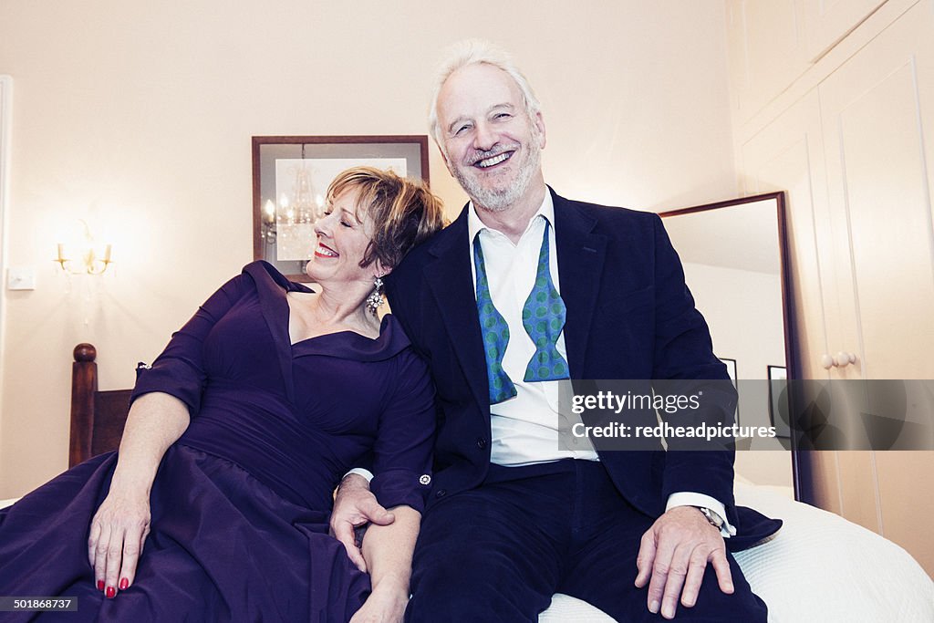 Couple sitting on bed, laughing