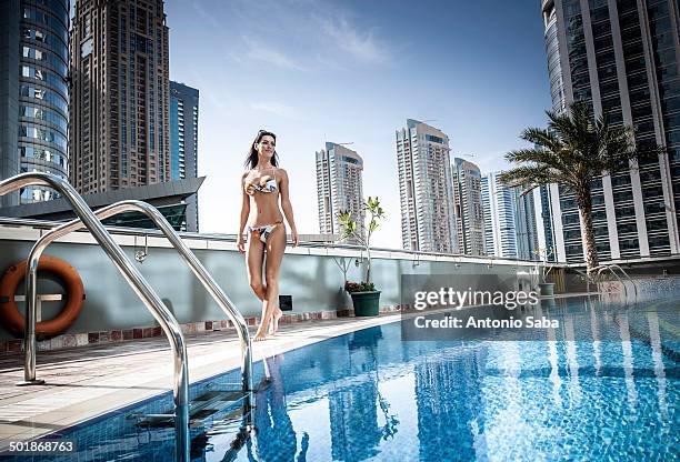 young woman in bikini at rooftop swimming pool, dubai, united arab emirates - ドバイ　ホテル ストックフォトと画像