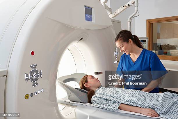 radiographer reassuring girl going into ct scanner - operating gown stock pictures, royalty-free photos & images