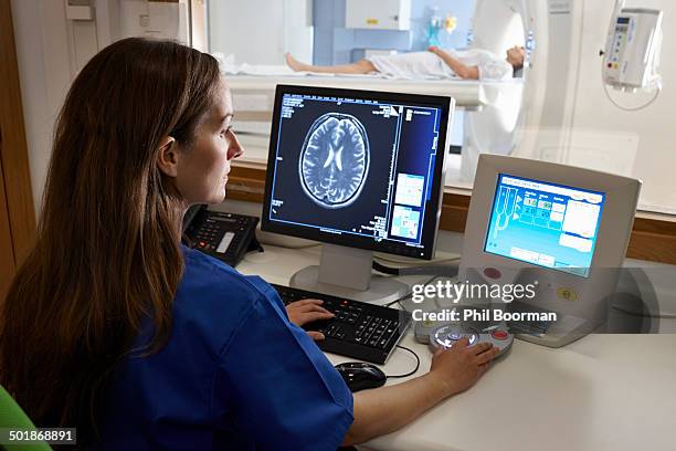 radiologist looking at brain scan image on computer screen - scientific imaging technique fotografías e imágenes de stock