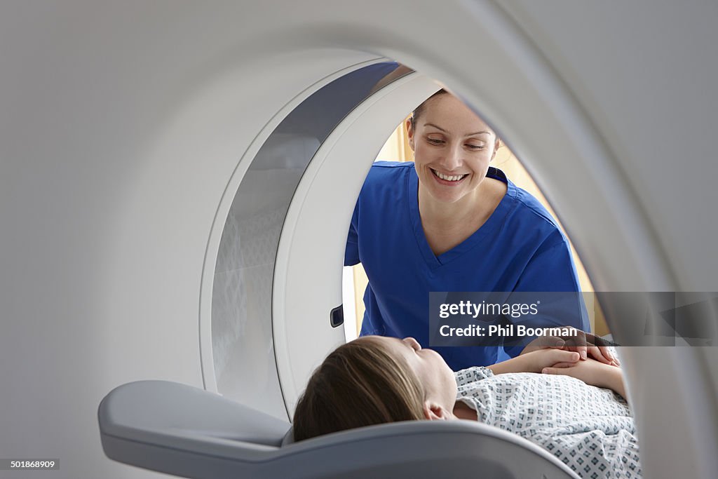 Radiographer smiling at girl inside CT scanner